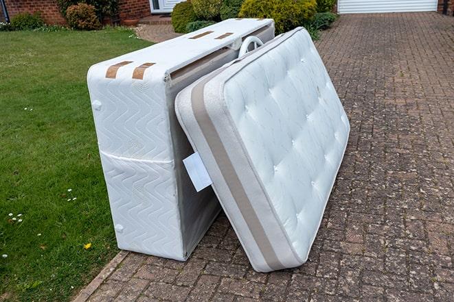 a mattress being taken away for recycling by a removal team